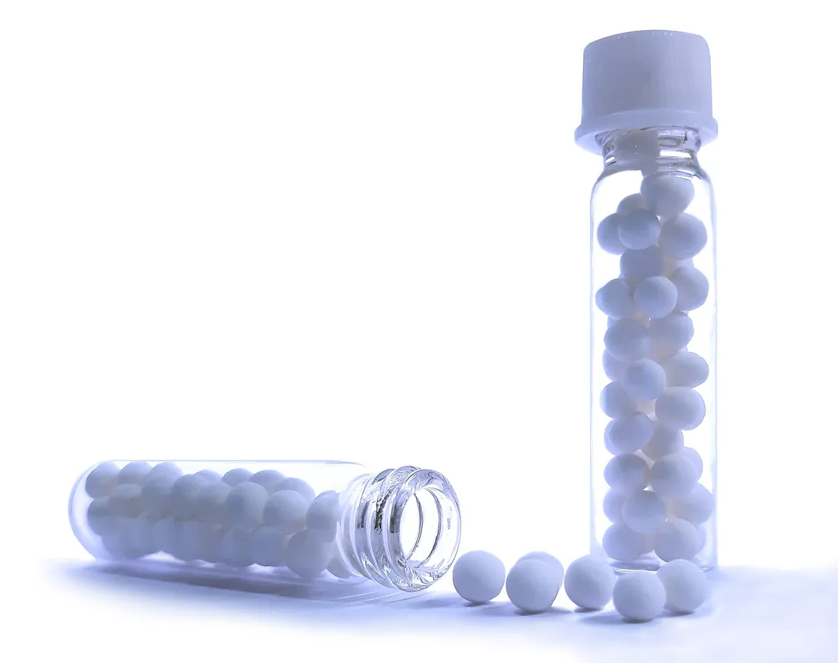 Biele homeopatické globuly v sklenených liekovkách