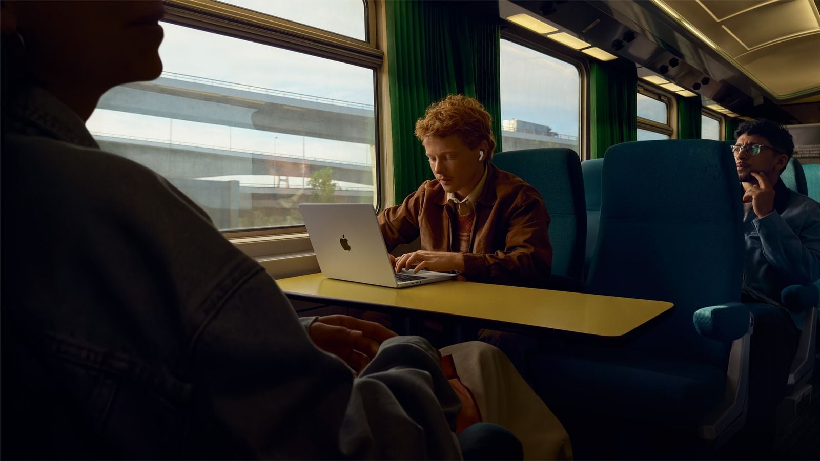 Človek s AirPods Pro 3 v ušiach počas cesty vlakom.