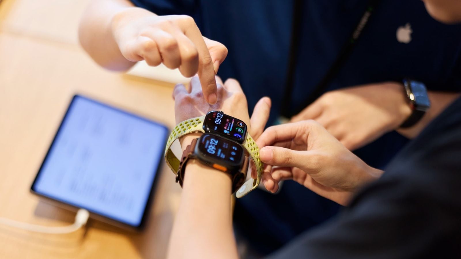 Detailný záber zápästia zákazníka skúšajúceho najnovšie modely Apple Watch v predajni Apple Jing'an