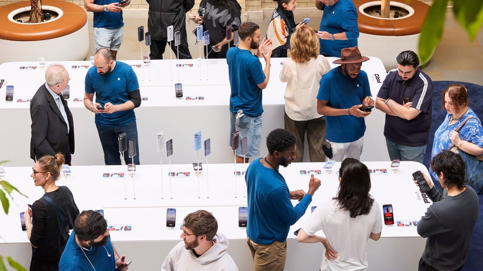 Zamestnanci pomáhajú zákazníkom pri vystavených iPhonoch v predajni Apple Covent Garden