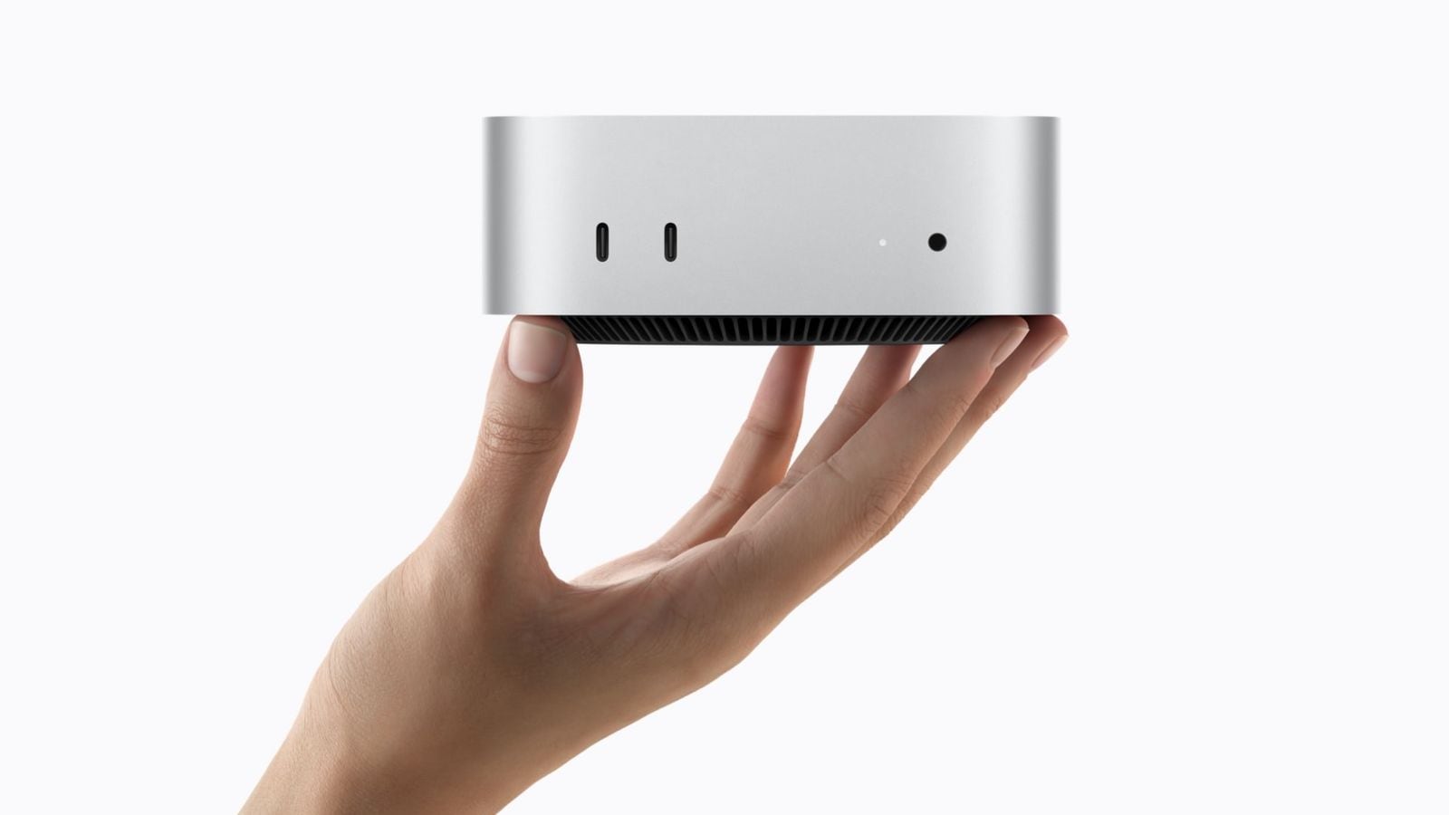 Ruka drží strieborný Mac mini so zobrazenými prednými portami