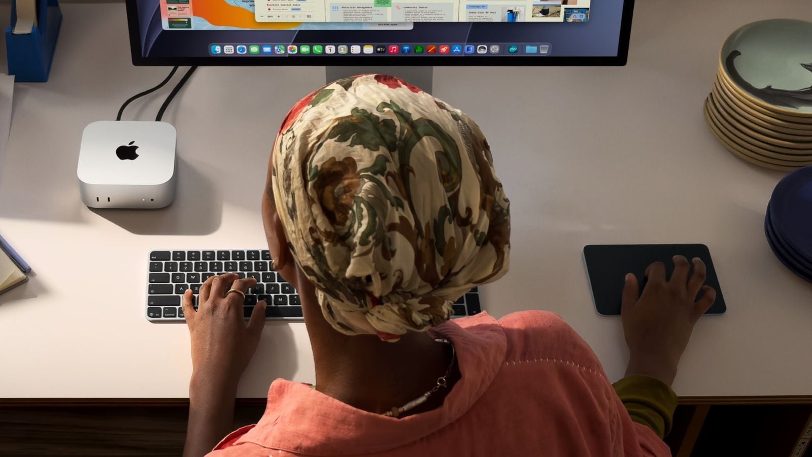 Pohľad zhora na osobu pri klávesnici a myši, Mac mini pripojený k veľkému displeju
